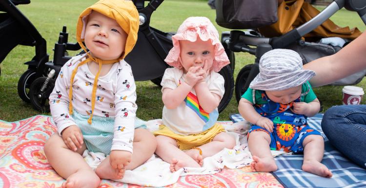 Three babies at a picnic in the park sitting on a blanket Three babies at a picnic in the park sitting on a blanket