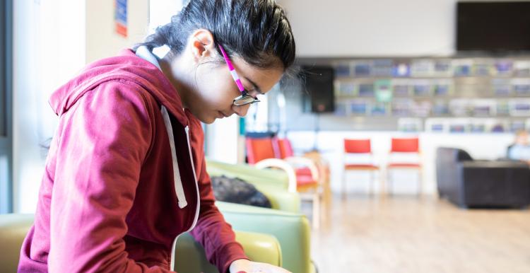 Young person using their phone in a waiting room Young person using their phone in a waiting room