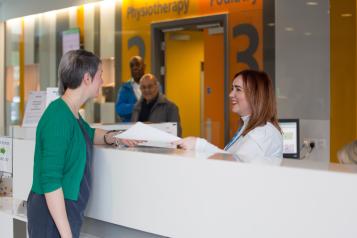 Woman speaking to someone at the hospital reception