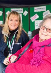 Healthwatch staff member at event talking to someone in a wheelchair